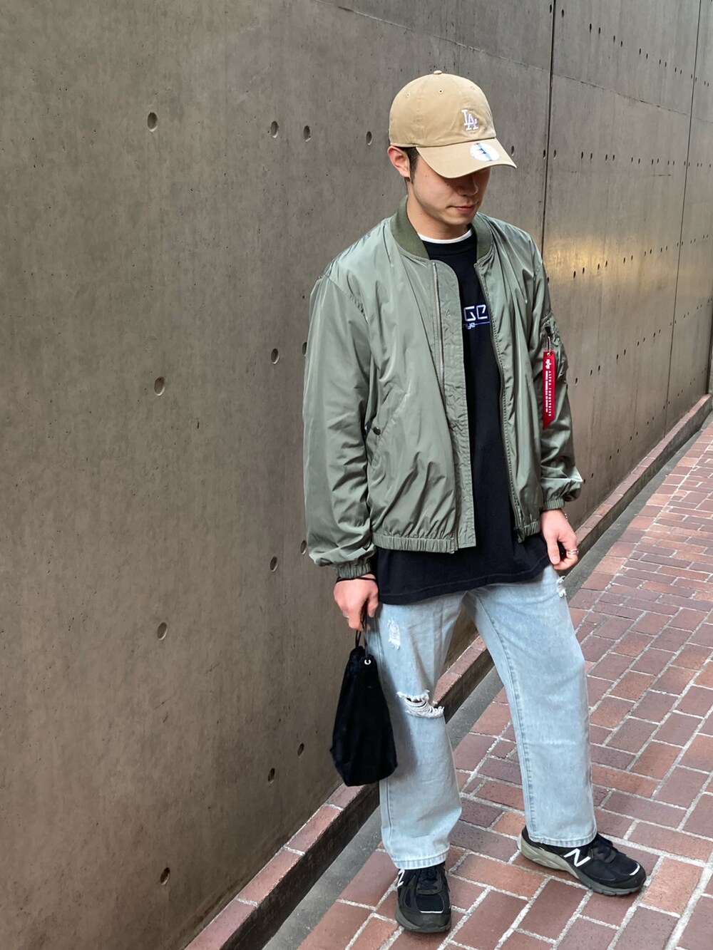 ブラック系のスニーカー、ブルー系のデニムパンツ、ブラック系のハンドバッグを着用したメンズの春コーディネートの2枚目の写真