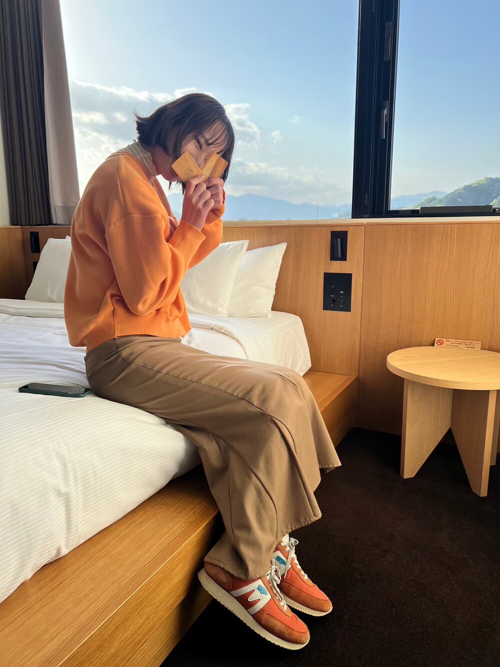 ベージュ系のスカート、オレンジ系のトップス、オレンジ系のスニーカーを着用したレディースの秋コーディネートの2枚目の写真