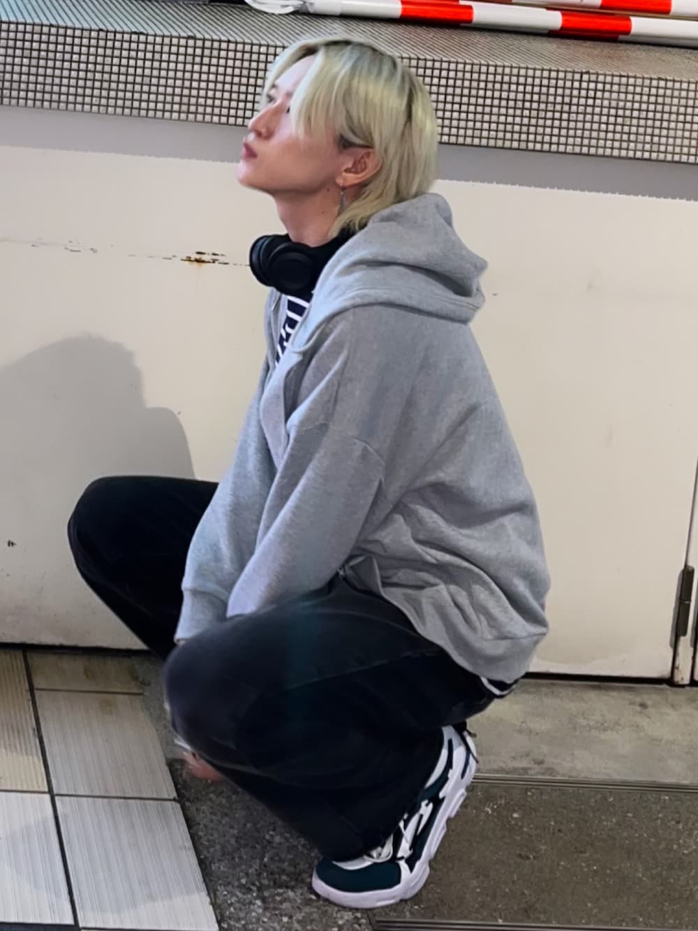 グレー系のパーカー、ブラック系のデニムパンツ、ホワイト系のスニーカーを着用したメンズの夏コーディネートの2枚目の写真