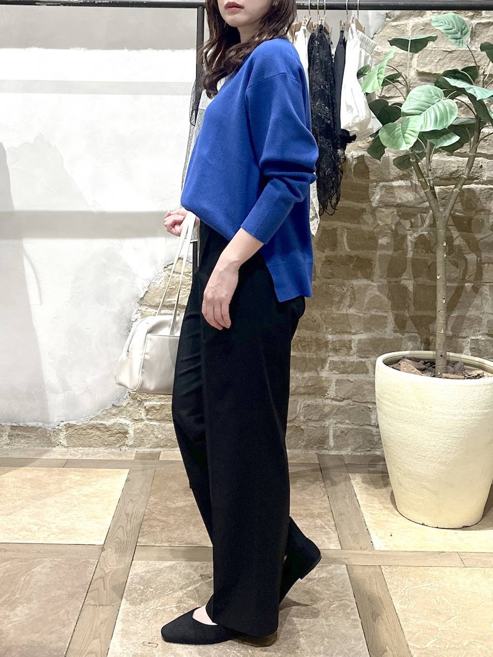 ブラック系のパンプス、ブラック系のスラックス、ブルー系のニット/セーターを着用したレディースの春コーディネートの2枚目の写真