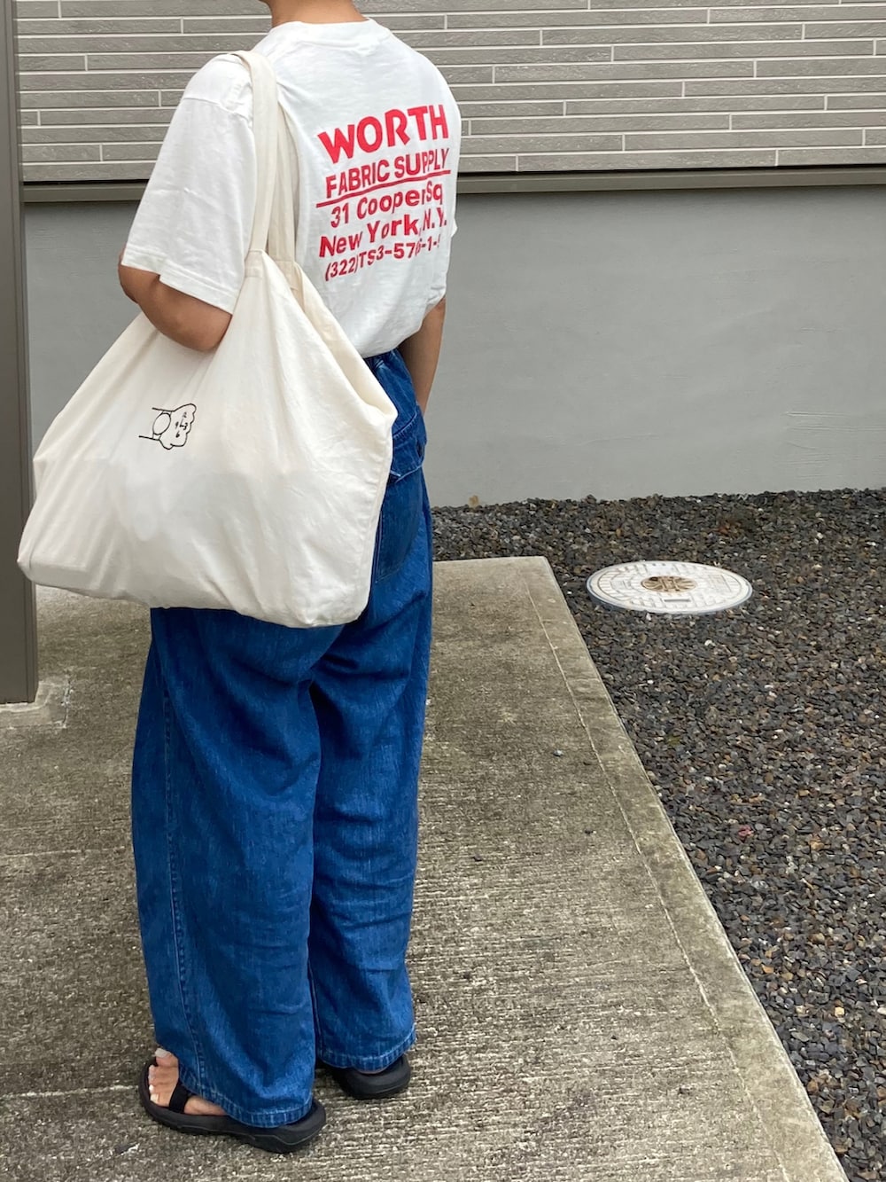 ホワイト系のTシャツ/カットソー、ブルー系のデニムパンツ、ホワイト系のトートバッグを着用したレディースの秋コーディネートの2枚目の写真