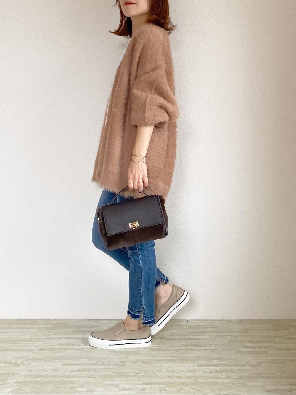 ブルー系のデニムパンツ、ブラウン系のカーディガン/ボレロ、ブラウン系のバッグを着用したレディースの秋コーディネートの2枚目の写真