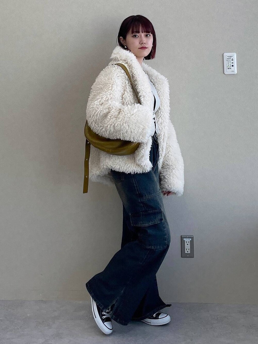 イエロー系のショルダーバッグ、ブルー系のデニムパンツ、ホワイト系のその他アウターを着用したレディースの冬コーディネートの2枚目の写真