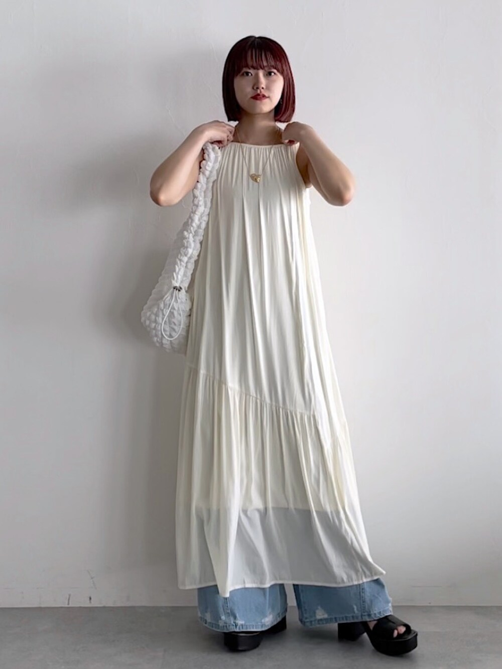 ホワイト系のワンピース、ホワイト系のショルダーバッグ、ブルー系のデニムパンツを着用したレディースの春コーディネートの5枚目の写真