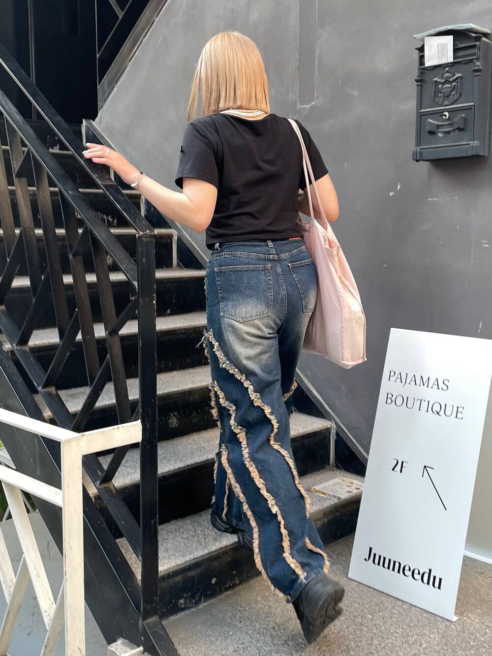 ブラック系のスニーカー、ブラック系のTシャツ/カットソー、ブルー系のデニムパンツを着用したレディースの夏コーディネートの4枚目の写真