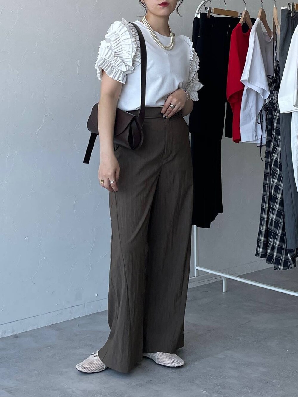 ブラウン系のショルダーバッグ、ホワイト系のTシャツ/カットソー、ブラウン系のその他パンツを着用したレディースの夏コーディネートの2枚目の写真