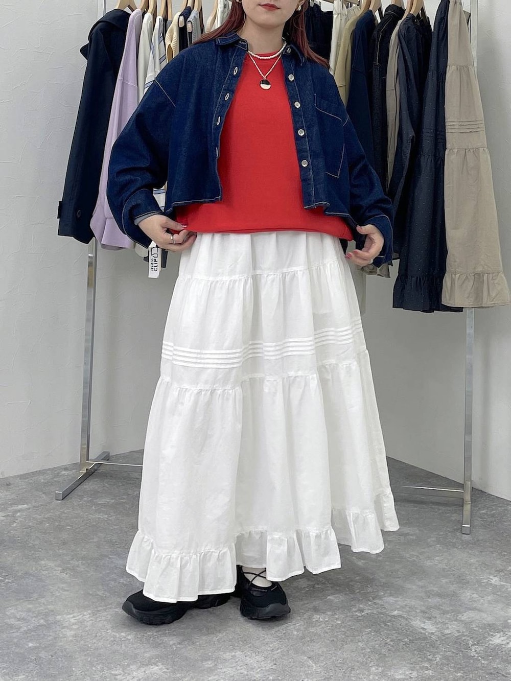 ブラック系のスニーカー、レッド系のスウェット、ホワイト系のスカートを着用したレディースの春コーディネートの6枚目の写真