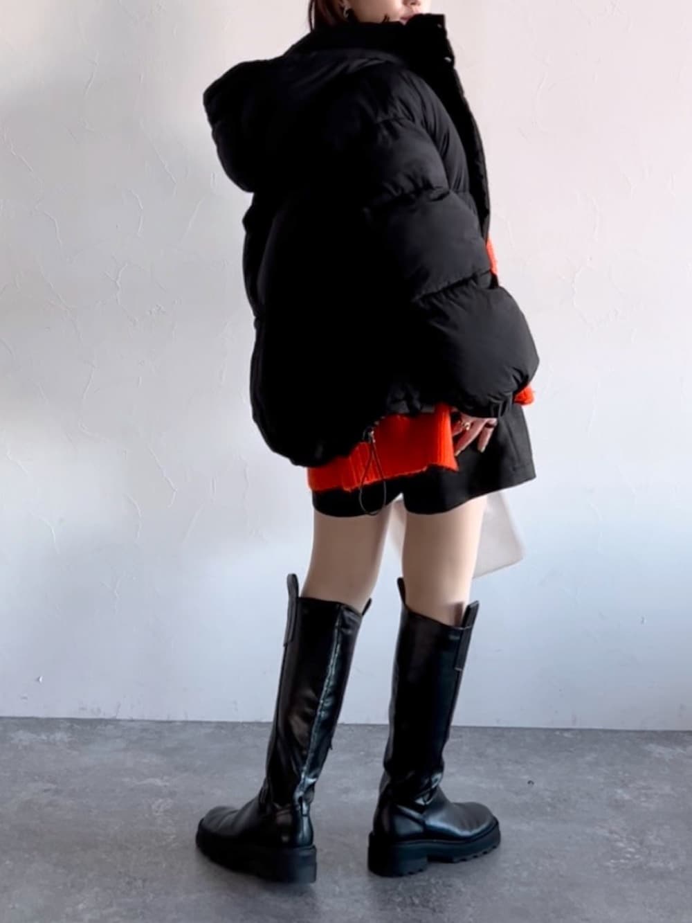 オレンジ系のニット/セーター、ブラック系のブルゾン、ブラック系のその他パンツを着用したレディースの冬コーディネートの7枚目の写真