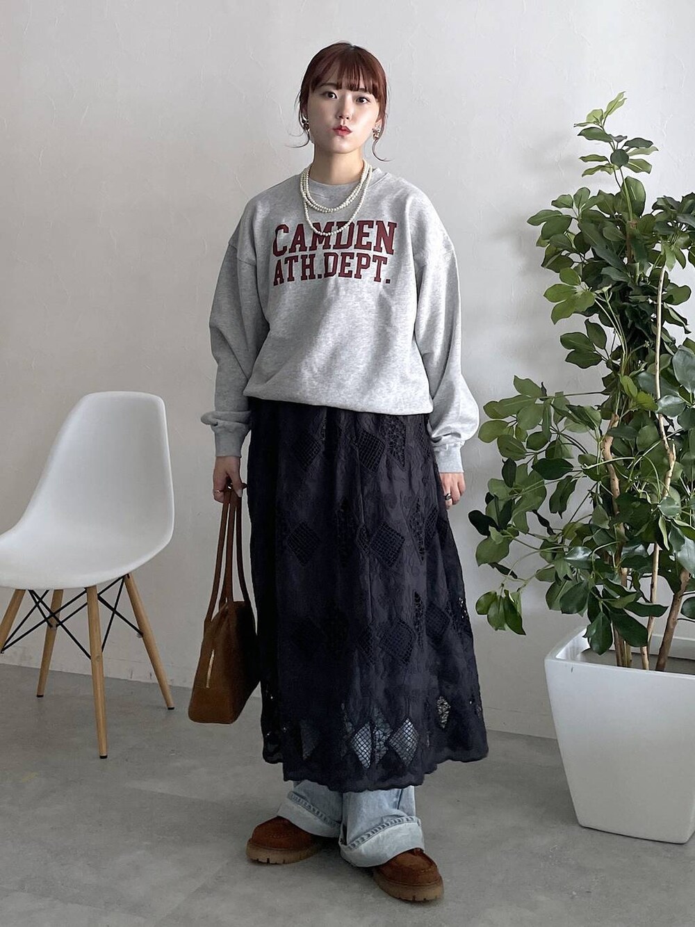 ブルー系のデニムパンツ、ブラック系のスカートを着用したレディースの秋コーディネートの2枚目の写真