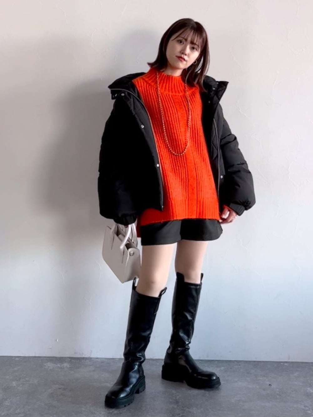 オレンジ系のニット/セーター、ブラック系のブルゾン、ブラック系のその他パンツを着用したレディースの冬コーディネートの5枚目の写真