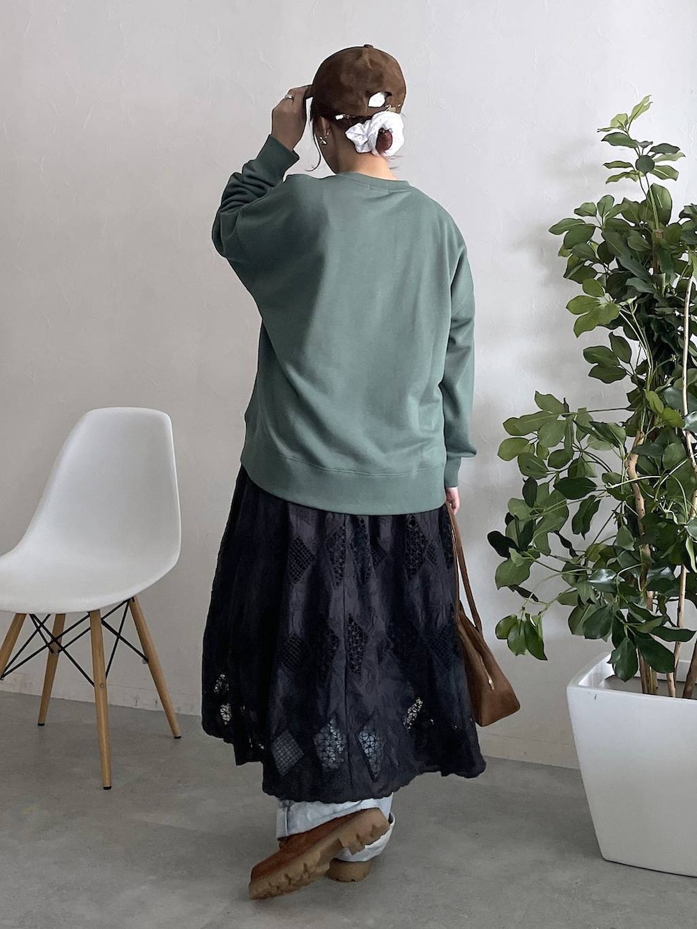 グリーン系のスウェット、ブルー系のデニムパンツ、ブラック系のスカートを着用したレディースの秋コーディネートの2枚目の写真