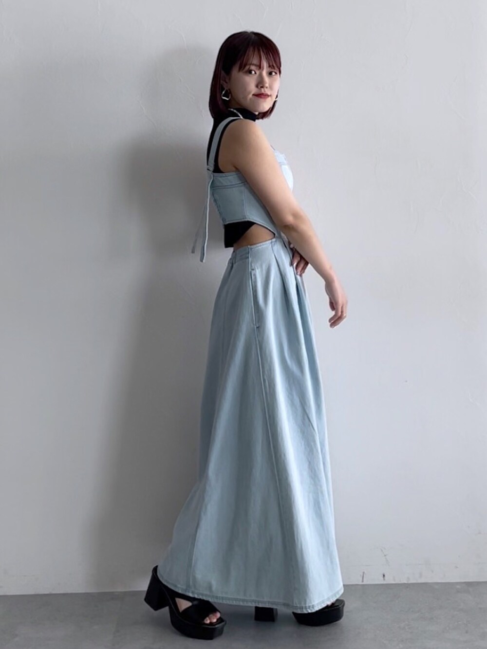 ブラック系のトップス、ブルー系のジャンパースカート、ブラック系のシューズを着用したレディースの春コーディネートの2枚目の写真