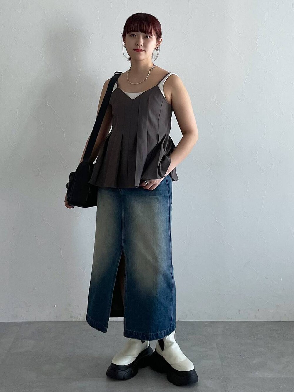 ブラック系のショルダーバッグ、ホワイト系のブーツ、ブルー系のスカートを着用したレディースの秋コーディネートの5枚目の写真