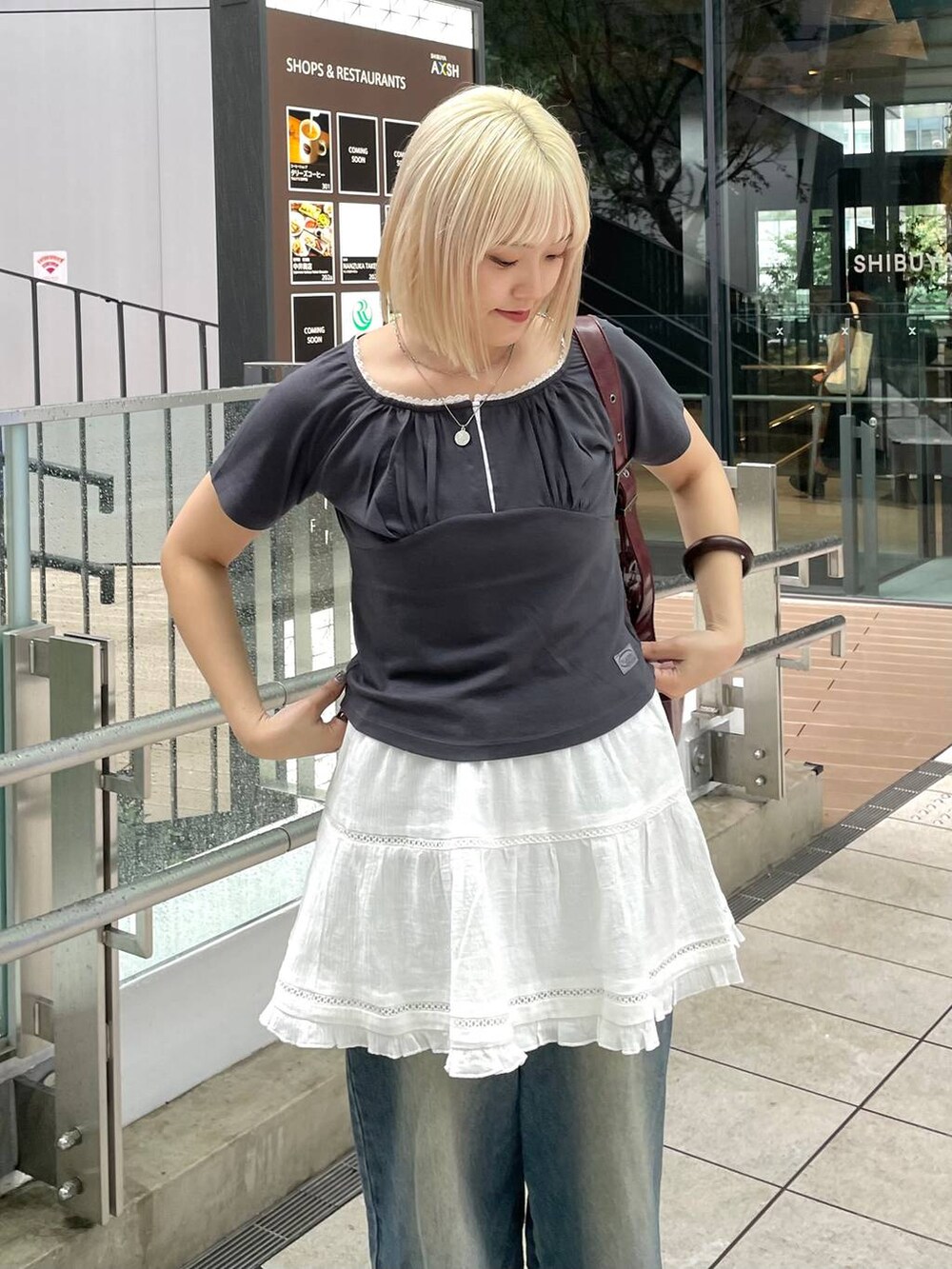 グレー系のTシャツ/カットソー、ホワイト系のスカート、レッド系のショルダーバッグを着用したレディースの秋コーディネートの2枚目の写真