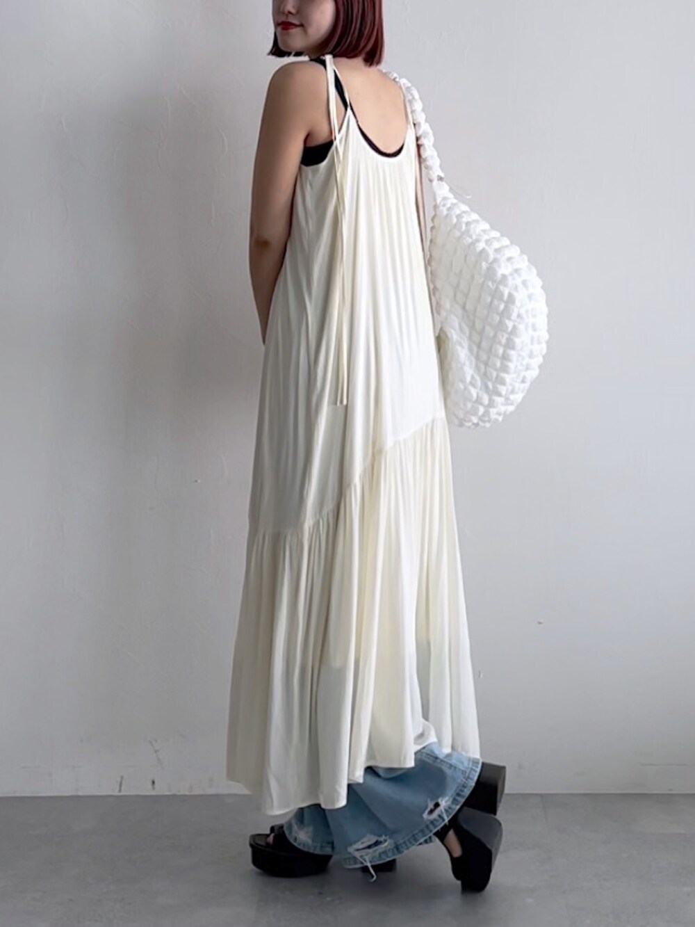 ホワイト系のワンピース、ホワイト系のショルダーバッグ、ブルー系のデニムパンツを着用したレディースの春コーディネートの2枚目の写真