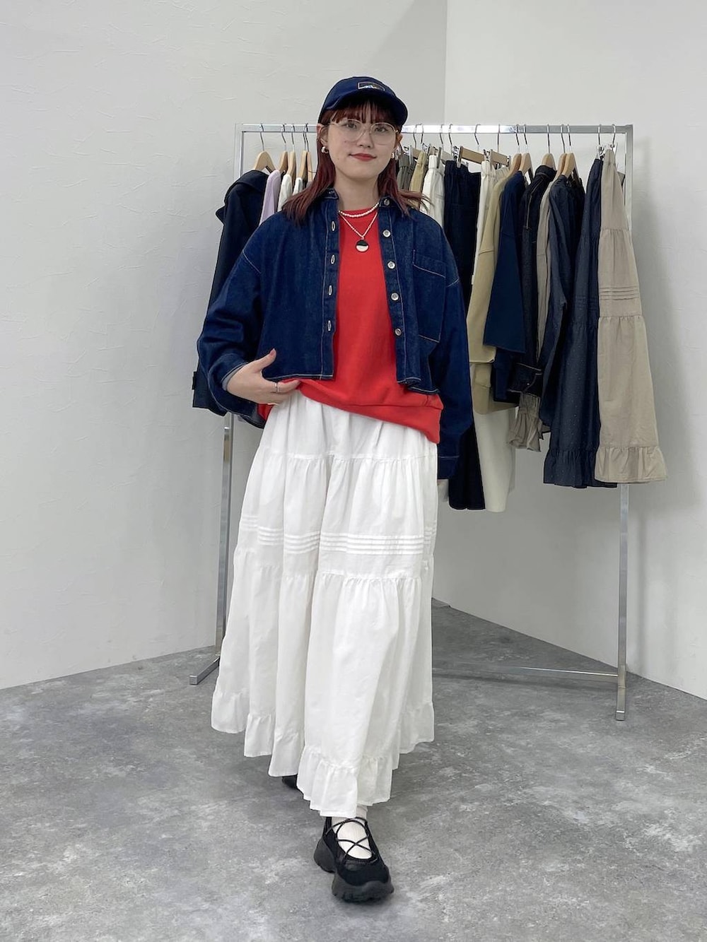 ブラック系のスニーカー、レッド系のスウェット、ホワイト系のスカートを着用したレディースの春コーディネートの2枚目の写真