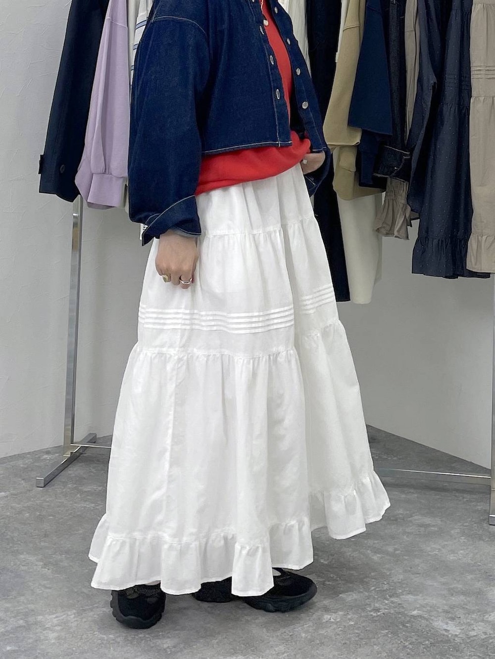 ブラック系のスニーカー、レッド系のスウェット、ホワイト系のスカートを着用したレディースの春コーディネートの3枚目の写真