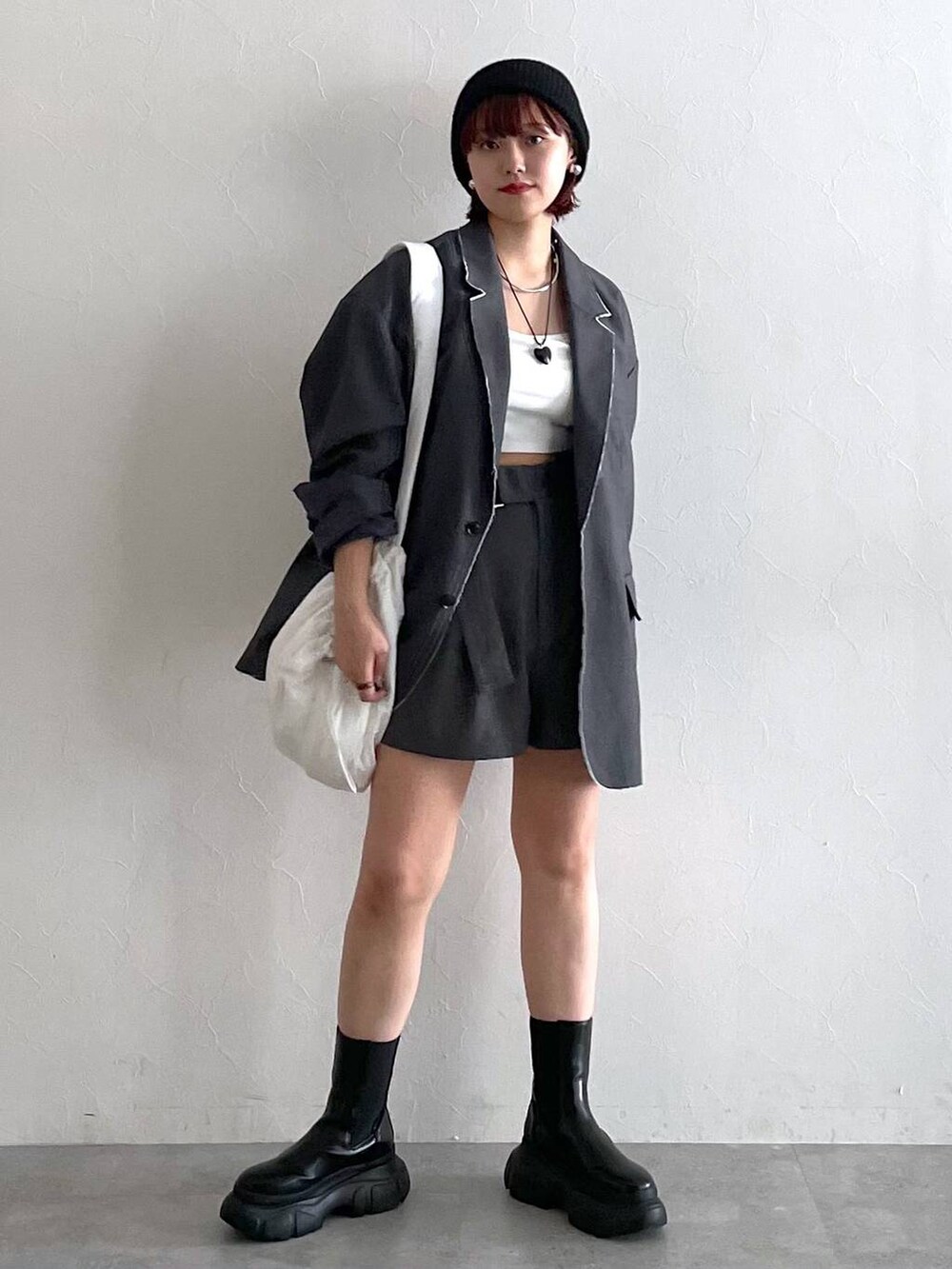 グレー系のテーラードジャケット、ブラック系のブーツ、ホワイト系のショルダーバッグを着用したレディースの秋コーディネートの7枚目の写真