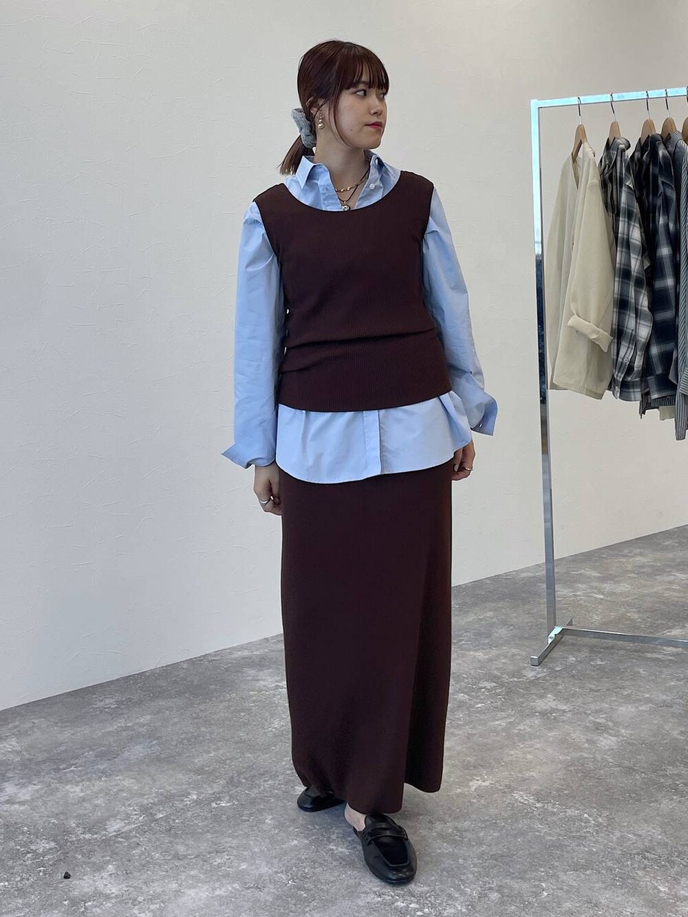 ブラウン系のニット/セーター、ブラウン系のスカート、ブルー系のシャツ/ブラウスを着用したレディースの秋コーディネートの6枚目の写真