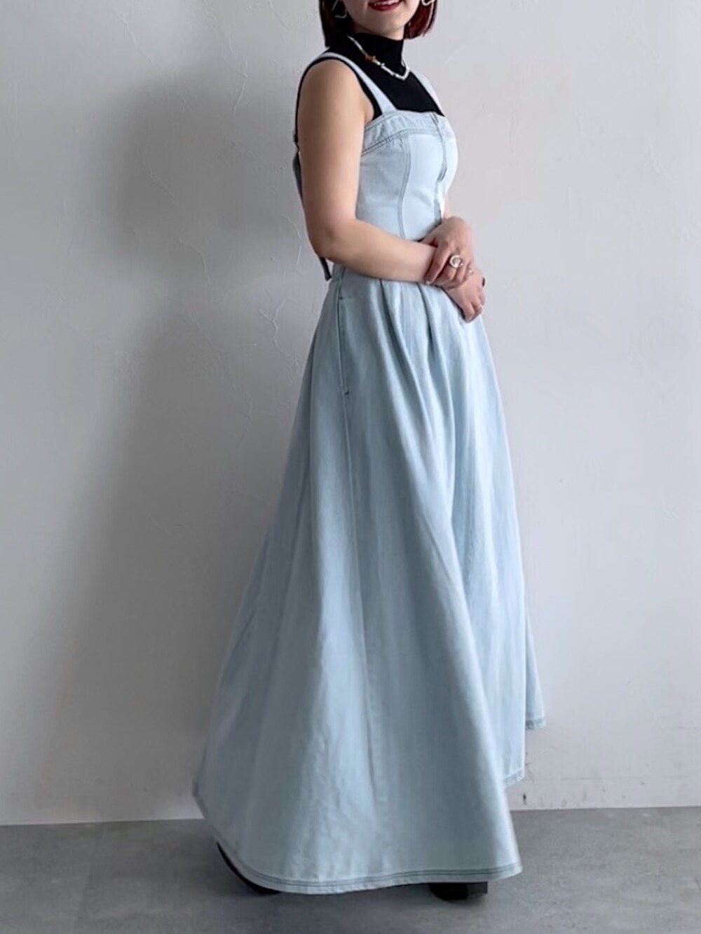 ブラック系のトップス、ブルー系のジャンパースカート、ブラック系のシューズを着用したレディースの春コーディネートの6枚目の写真