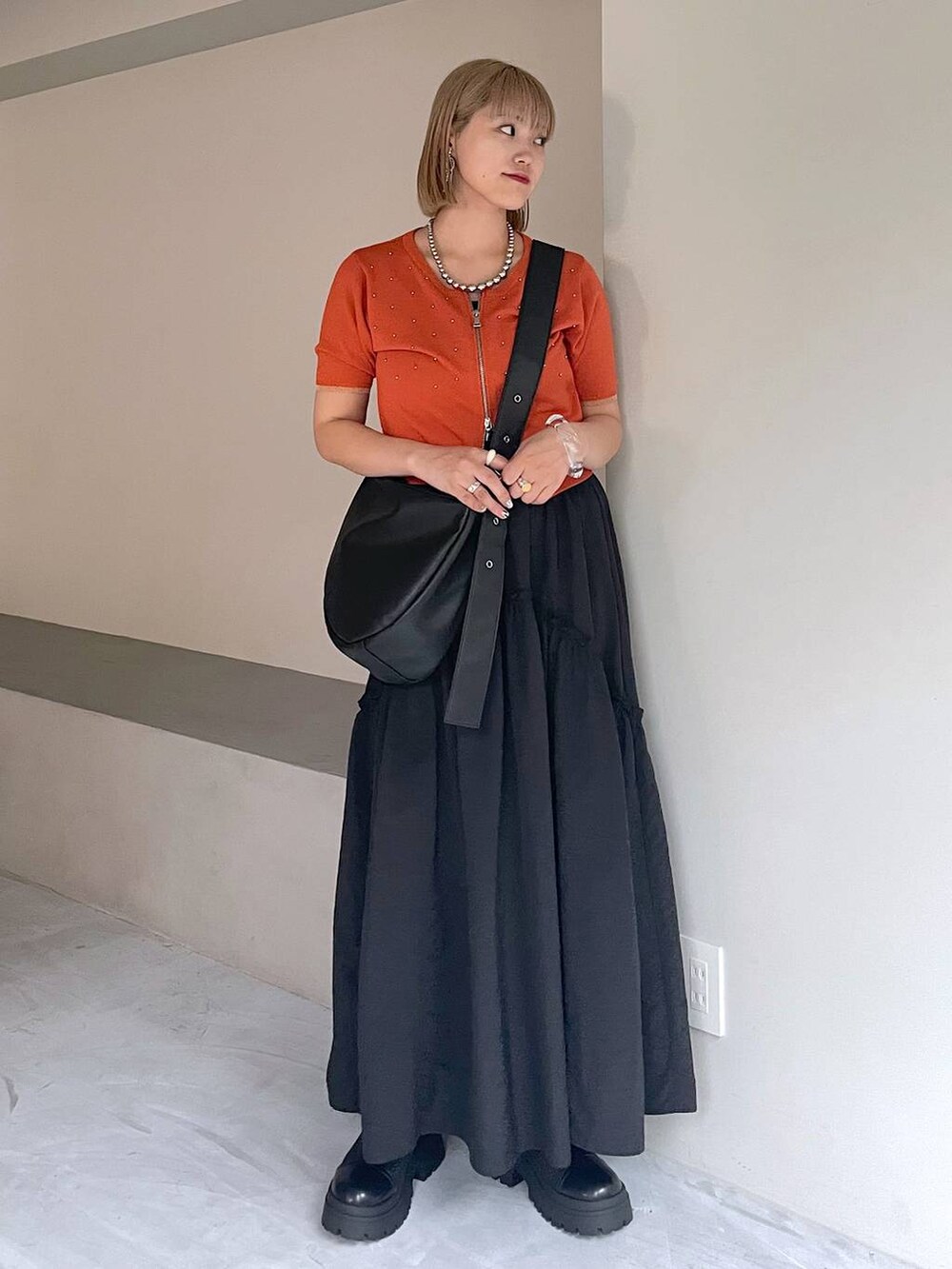 ブラック系のブーツ、ブラック系のスカート、ブラック系のショルダーバッグを着用したレディースの夏コーディネートの5枚目の写真