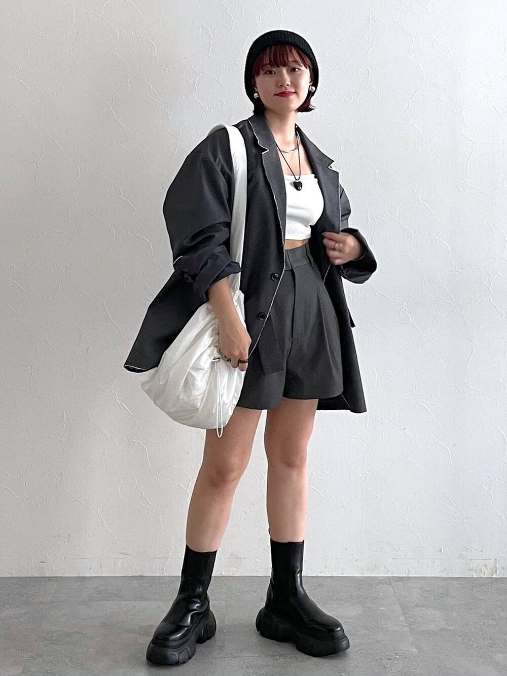 グレー系のテーラードジャケット、ブラック系のブーツ、ホワイト系のショルダーバッグを着用したレディースの秋コーディネートの8枚目の写真