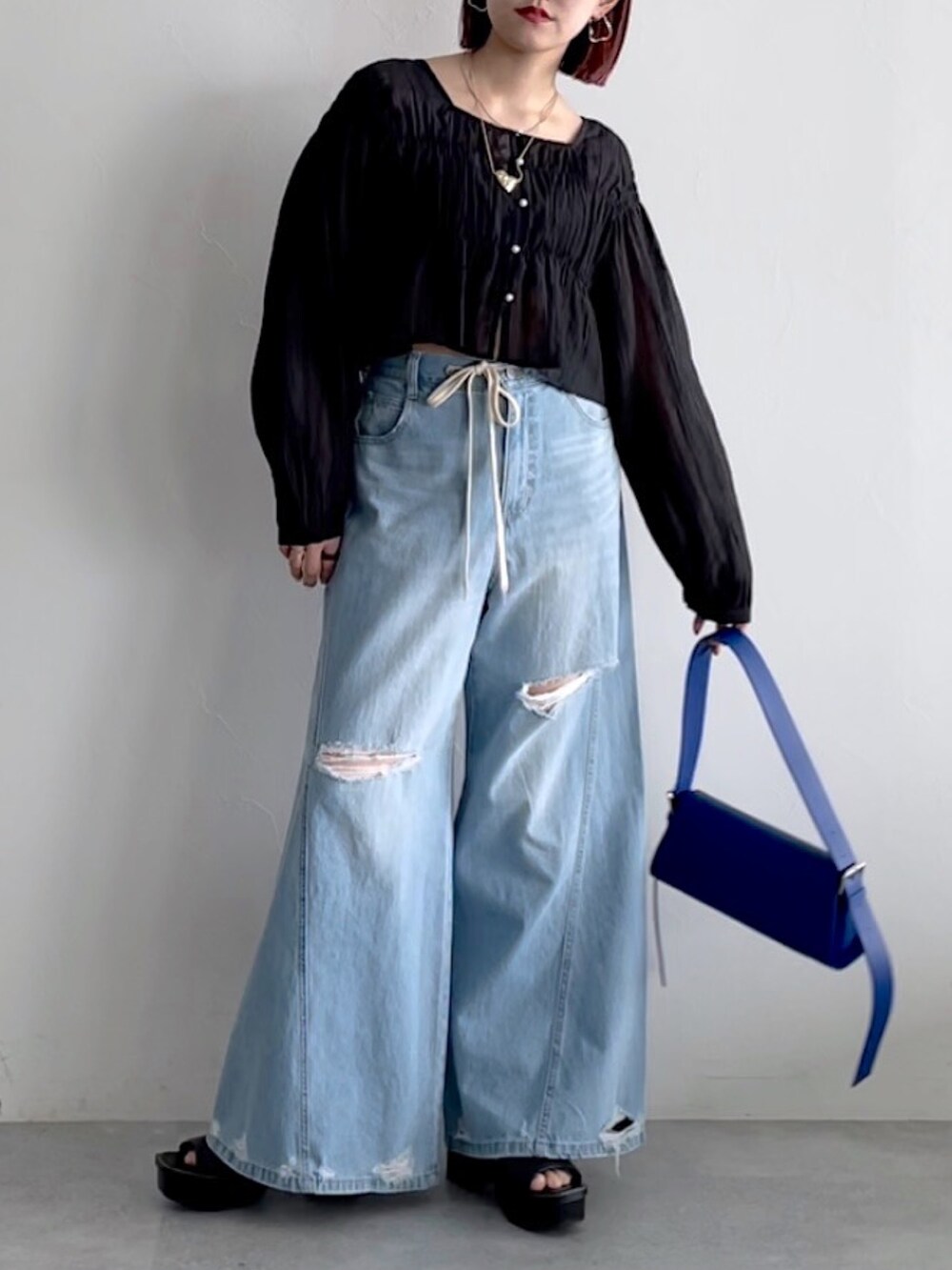 ブルー系のデニムパンツ、ブラック系のシューズ、ブラック系のシャツ/ブラウスを着用したレディースの春コーディネートの2枚目の写真