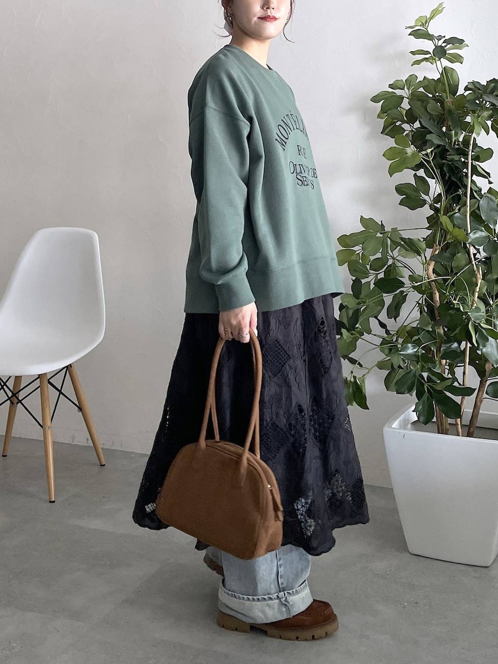 グリーン系のスウェット、ブルー系のデニムパンツ、ブラック系のスカートを着用したレディースの秋コーディネートの3枚目の写真