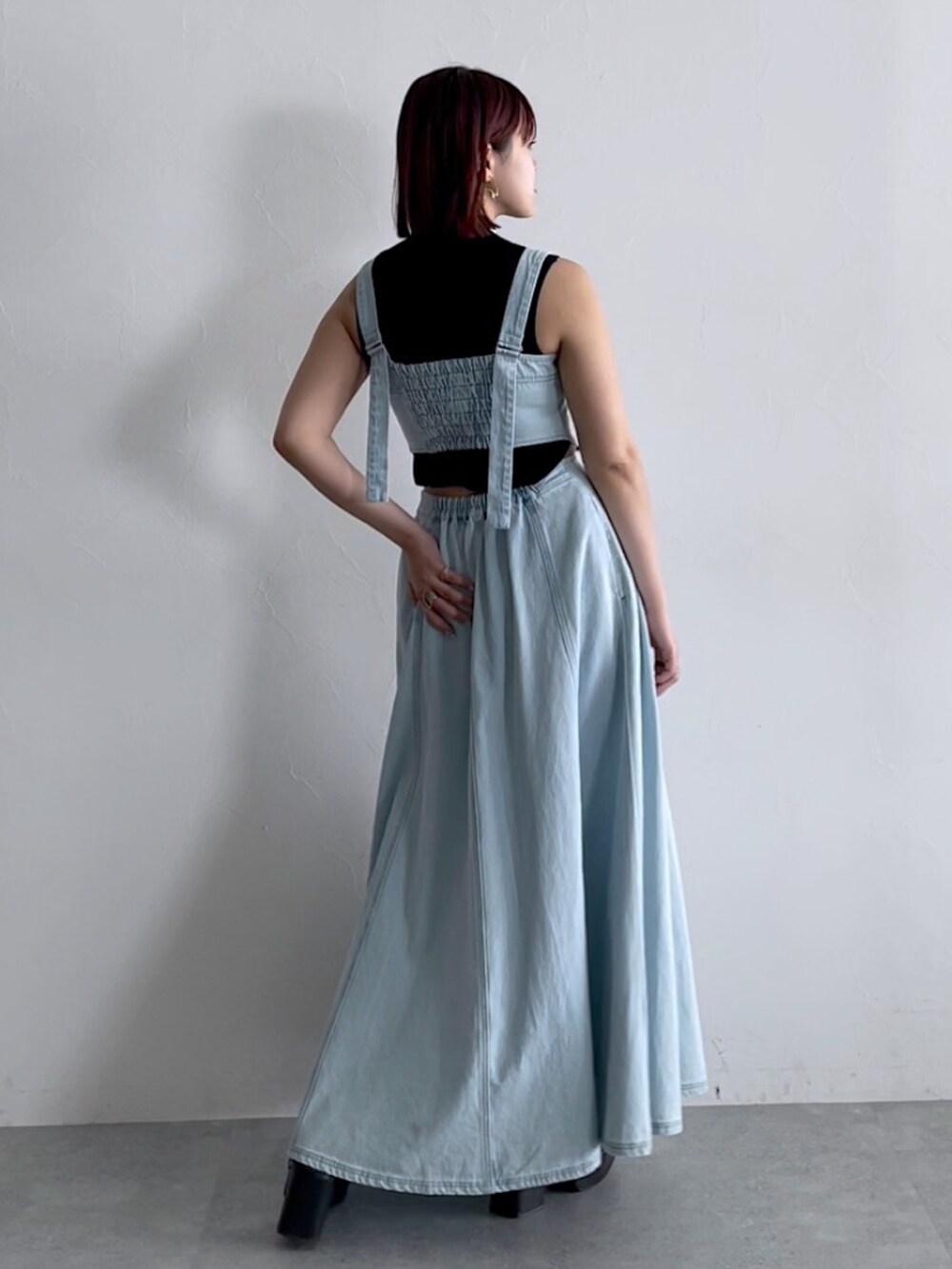 ブラック系のトップス、ブルー系のジャンパースカート、ブラック系のシューズを着用したレディースの春コーディネートの4枚目の写真