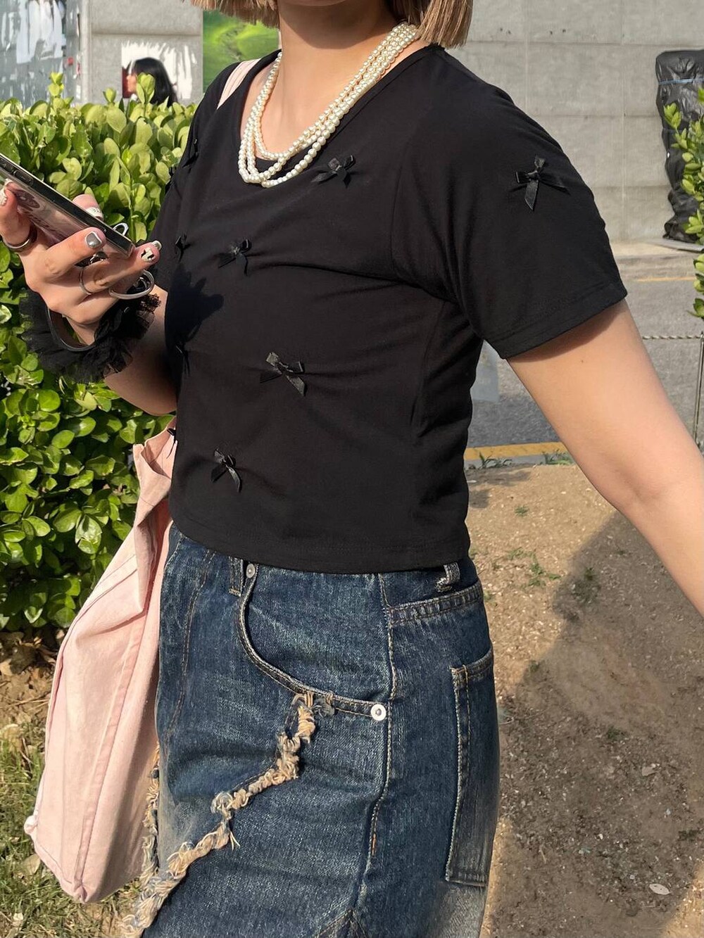 ブラック系のスニーカー、ブラック系のTシャツ/カットソー、ブルー系のデニムパンツを着用したレディースの夏コーディネートの3枚目の写真