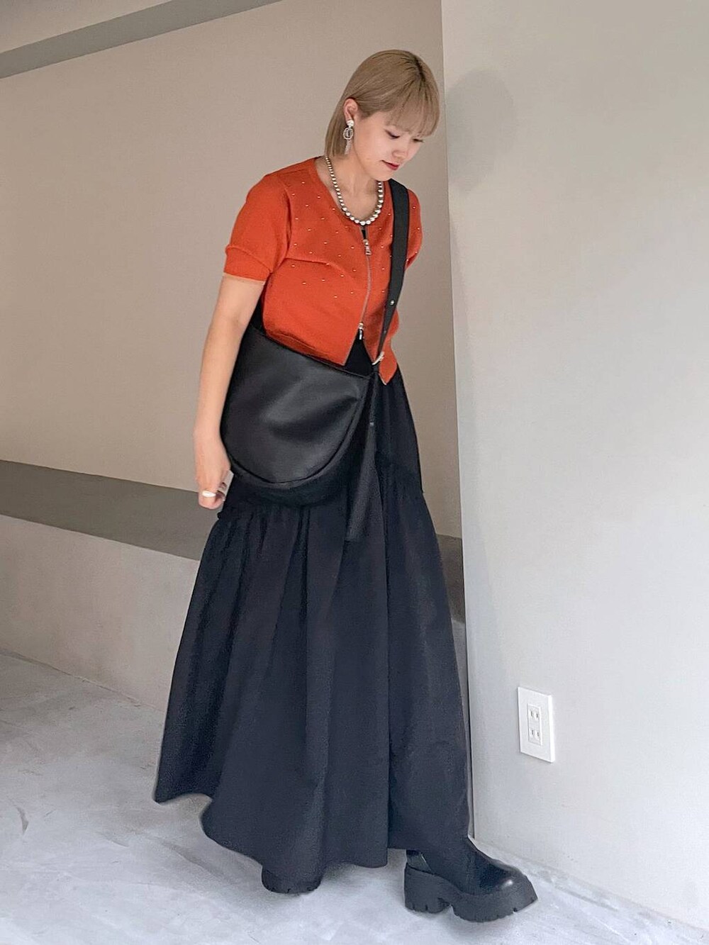 ブラック系のブーツ、ブラック系のスカート、ブラック系のショルダーバッグを着用したレディースの夏コーディネートの6枚目の写真