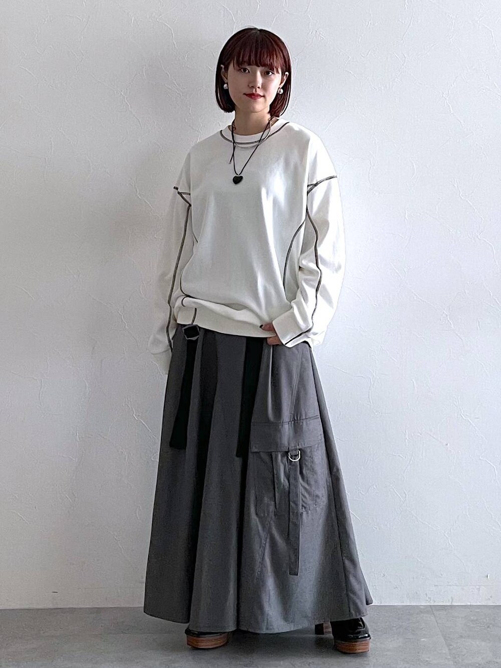 ホワイト系のスウェット、ブラック系のローファー、グレー系のジャンパースカートを着用したレディースの秋コーディネートの4枚目の写真