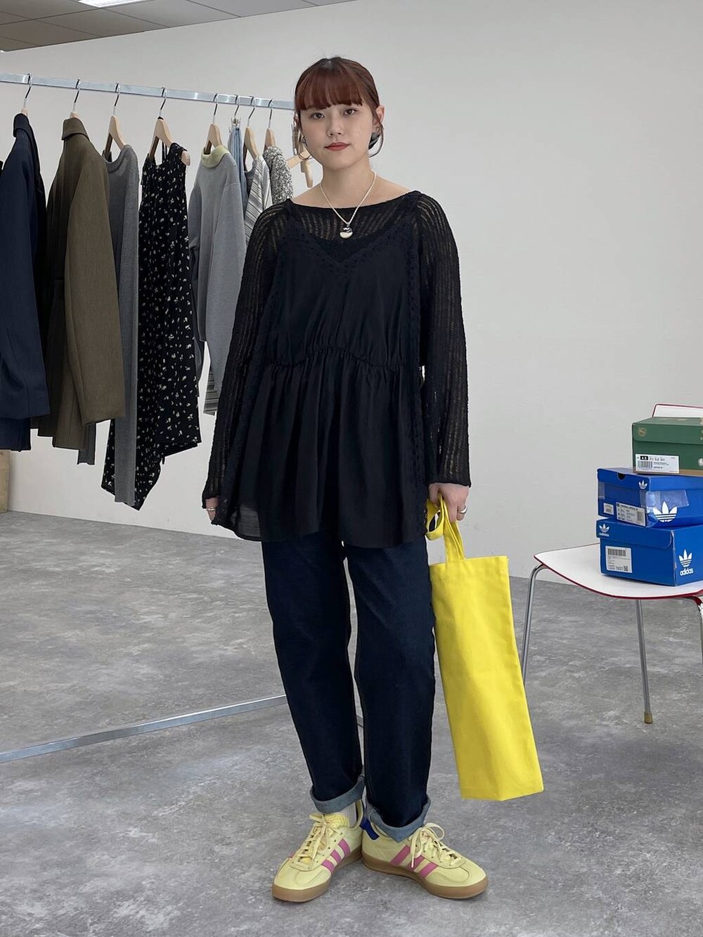 イエロー系のトートバッグ、ブルー系のデニムパンツ、ブラック系のキャミソールを着用したレディースの春コーディネートの4枚目の写真