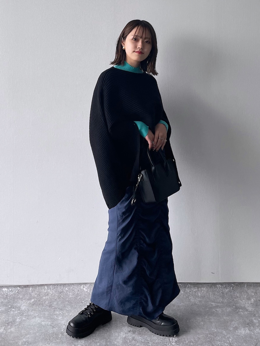 ブラック系のワンピース、ブルー系のニット/セーター、ブラック系のショルダーバッグを着用したレディースの冬コーディネートの2枚目の写真