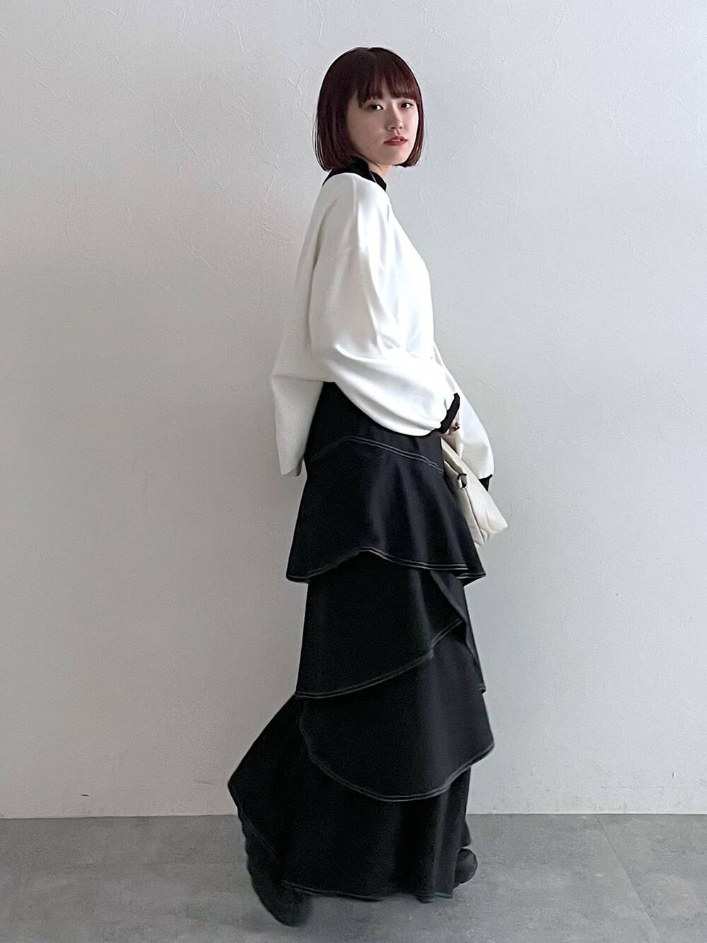 ホワイト系のニット/セーター、ホワイト系のクラッチバッグ、ブラック系のスカートを着用したレディースの秋コーディネートの2枚目の写真