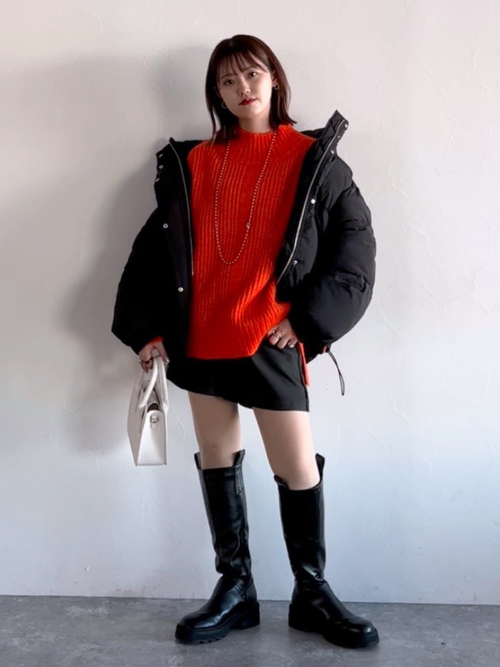 オレンジ系のニット/セーター、ブラック系のブルゾン、ブラック系のその他パンツを着用したレディースの冬コーディネートの6枚目の写真