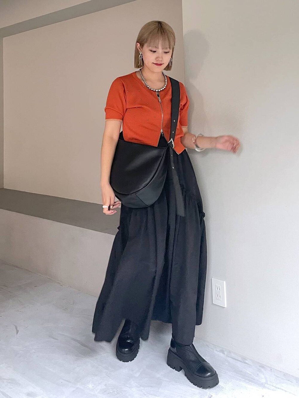 ブラック系のブーツ、ブラック系のスカート、ブラック系のショルダーバッグを着用したレディースの夏コーディネートの4枚目の写真