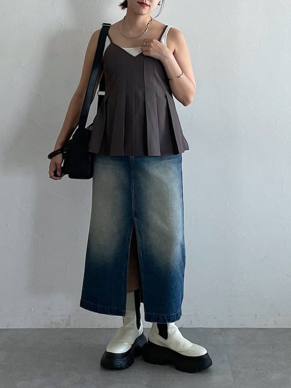 ブラック系のショルダーバッグ、ホワイト系のブーツ、ブルー系のスカートを着用したレディースの秋コーディネートの3枚目の写真