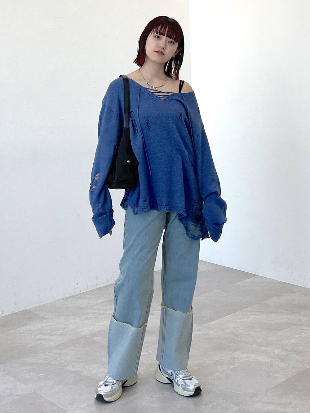 ブラック系のショルダーバッグ、ブルー系のニット/セーター、ブルー系のデニムパンツを着用したレディースの春コーディネートの5枚目の写真