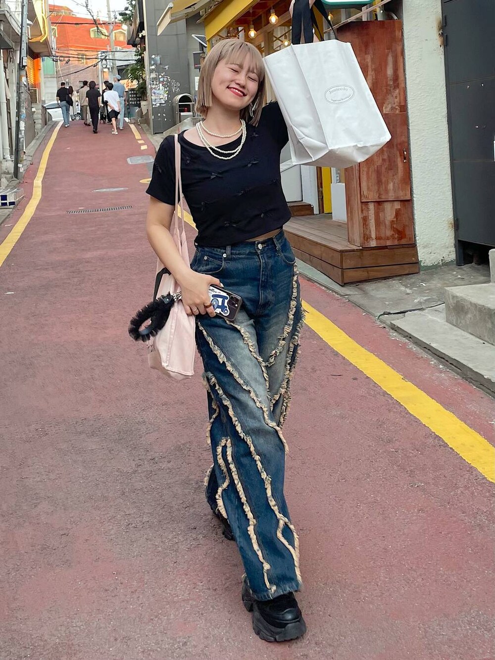 ブラック系のスニーカー、ブラック系のTシャツ/カットソー、ブルー系のデニムパンツを着用したレディースの夏コーディネートの5枚目の写真