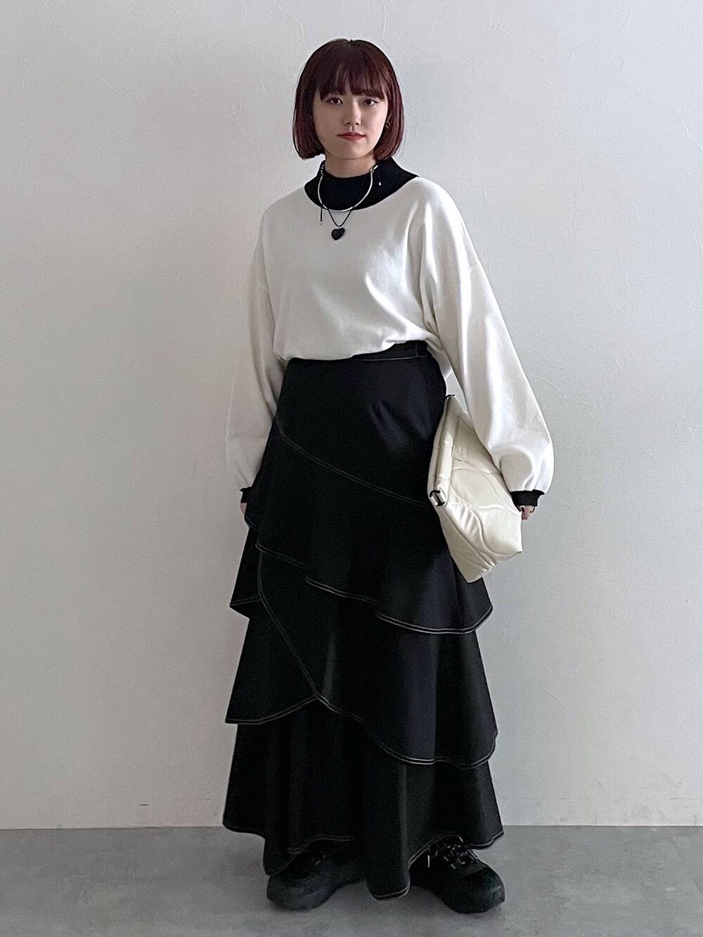 ホワイト系のニット/セーター、ホワイト系のクラッチバッグ、ブラック系のスカートを着用したレディースの秋コーディネートの5枚目の写真