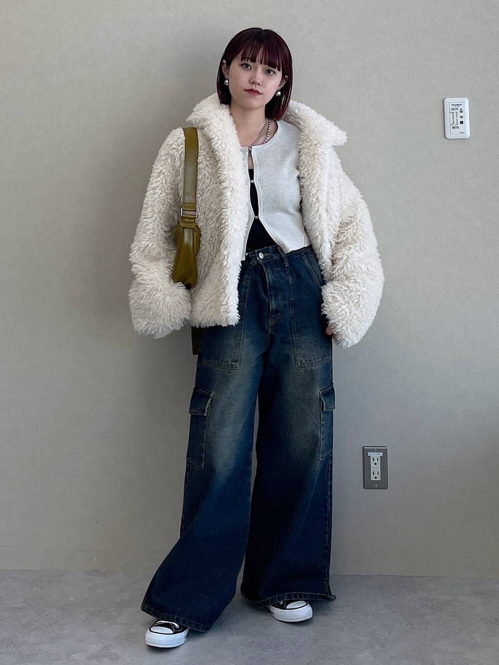 イエロー系のショルダーバッグ、ブルー系のデニムパンツ、ホワイト系のその他アウターを着用したレディースの冬コーディネートの4枚目の写真