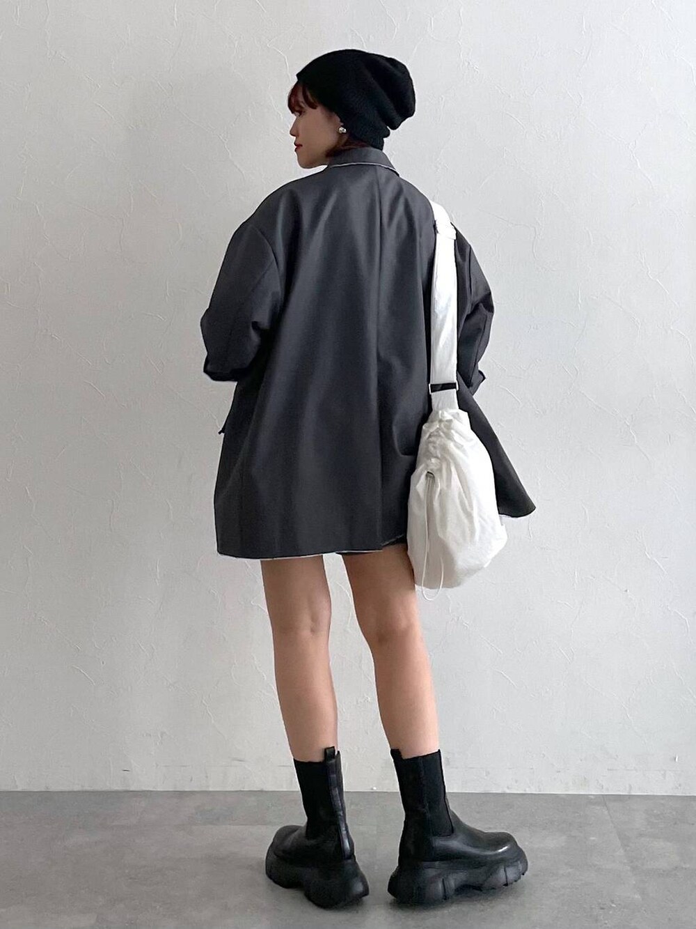 グレー系のテーラードジャケット、ブラック系のブーツ、ホワイト系のショルダーバッグを着用したレディースの秋コーディネートの5枚目の写真