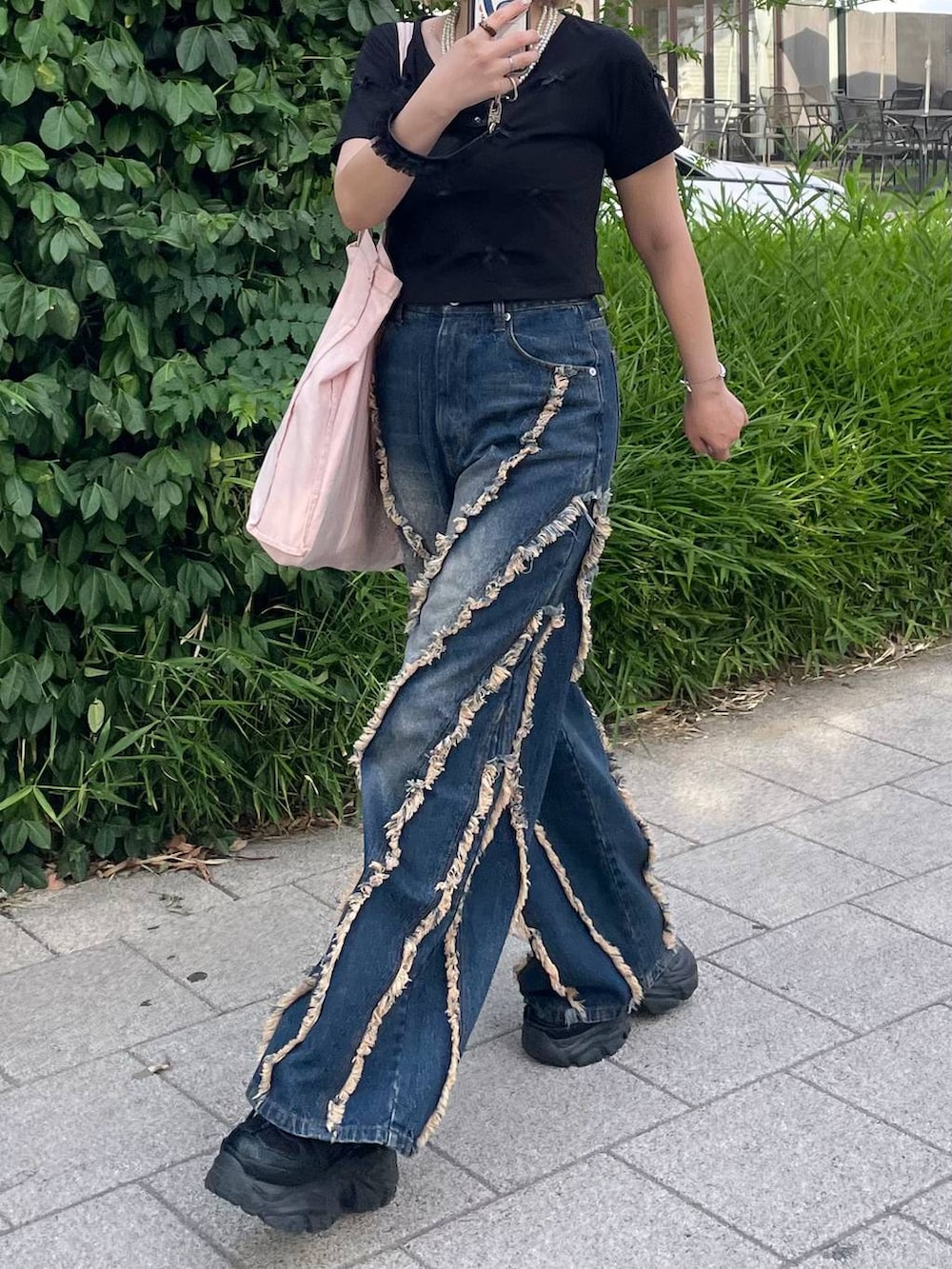 ブラック系のスニーカー、ブラック系のTシャツ/カットソー、ブルー系のデニムパンツを着用したレディースの夏コーディネートの2枚目の写真