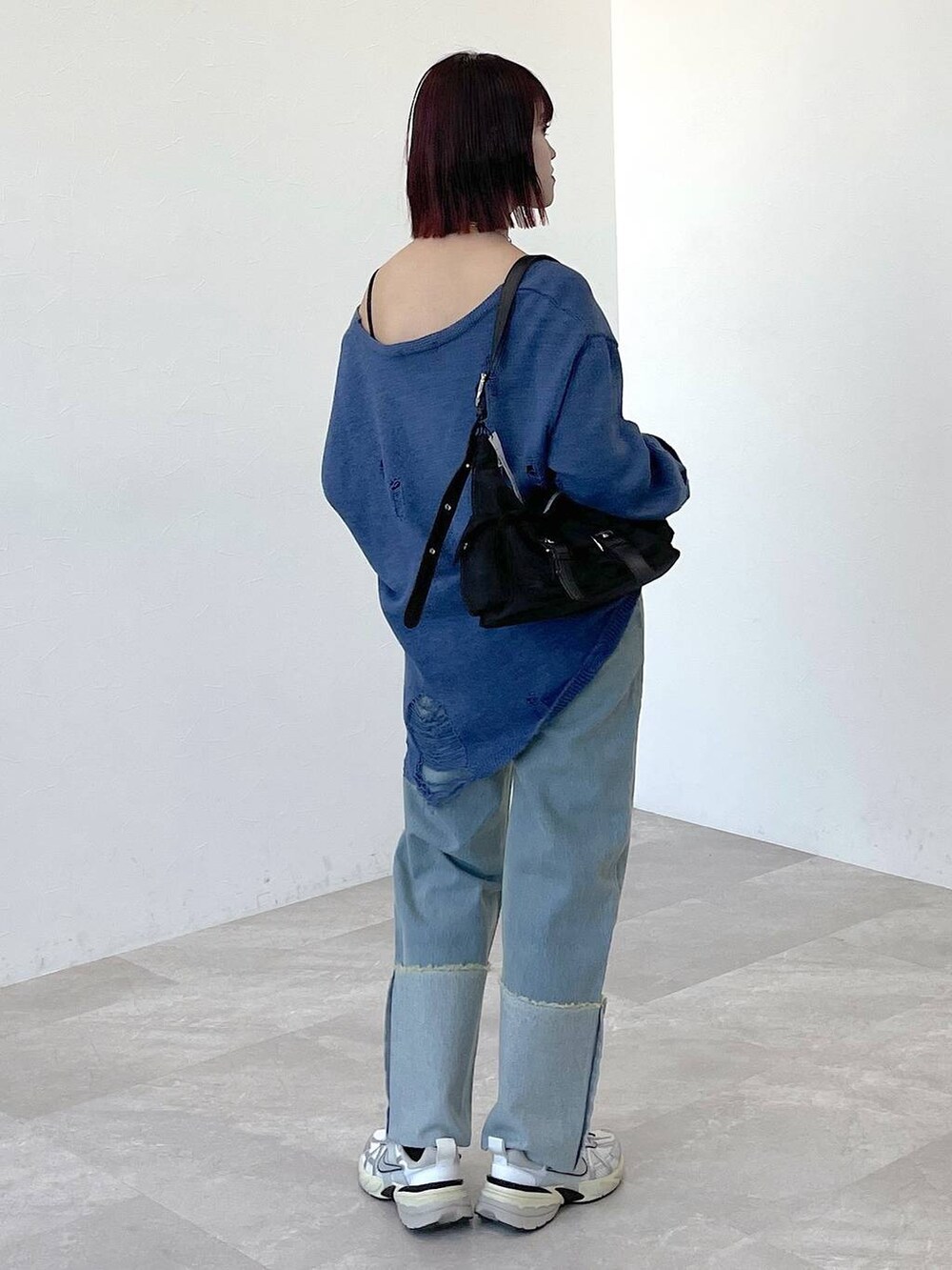 ブラック系のショルダーバッグ、ブルー系のニット/セーター、ブルー系のデニムパンツを着用したレディースの春コーディネートの3枚目の写真