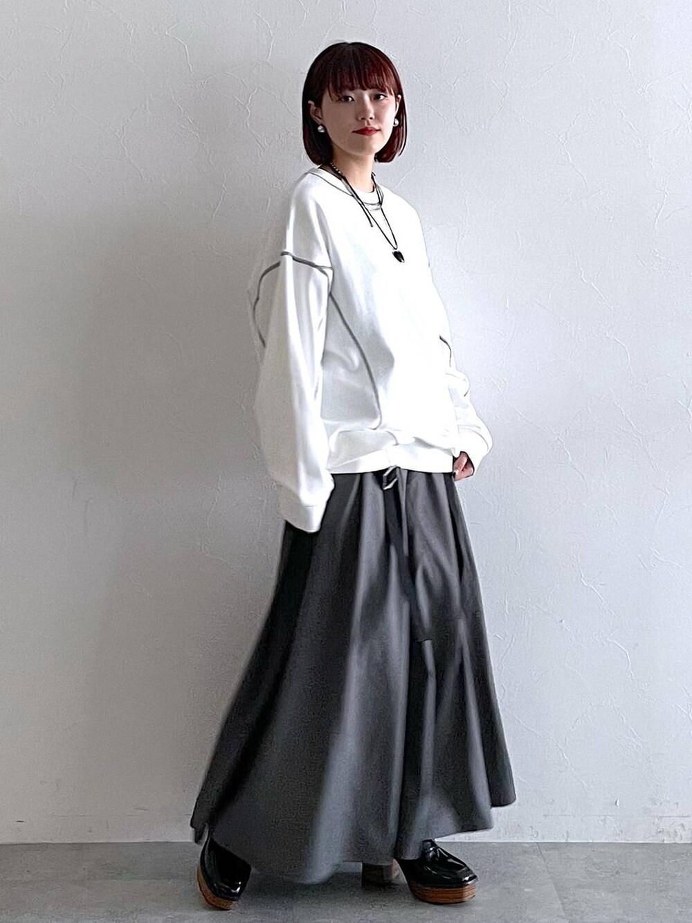 ホワイト系のスウェット、ブラック系のローファー、グレー系のジャンパースカートを着用したレディースの秋コーディネートの5枚目の写真