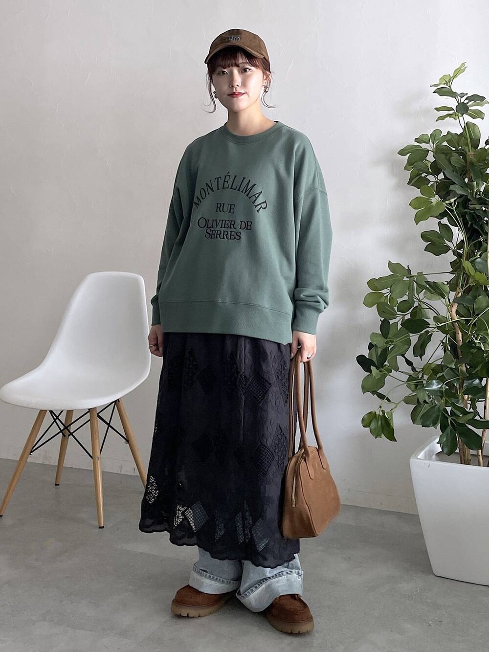 グリーン系のスウェット、ブルー系のデニムパンツ、ブラック系のスカートを着用したレディースの秋コーディネートの5枚目の写真