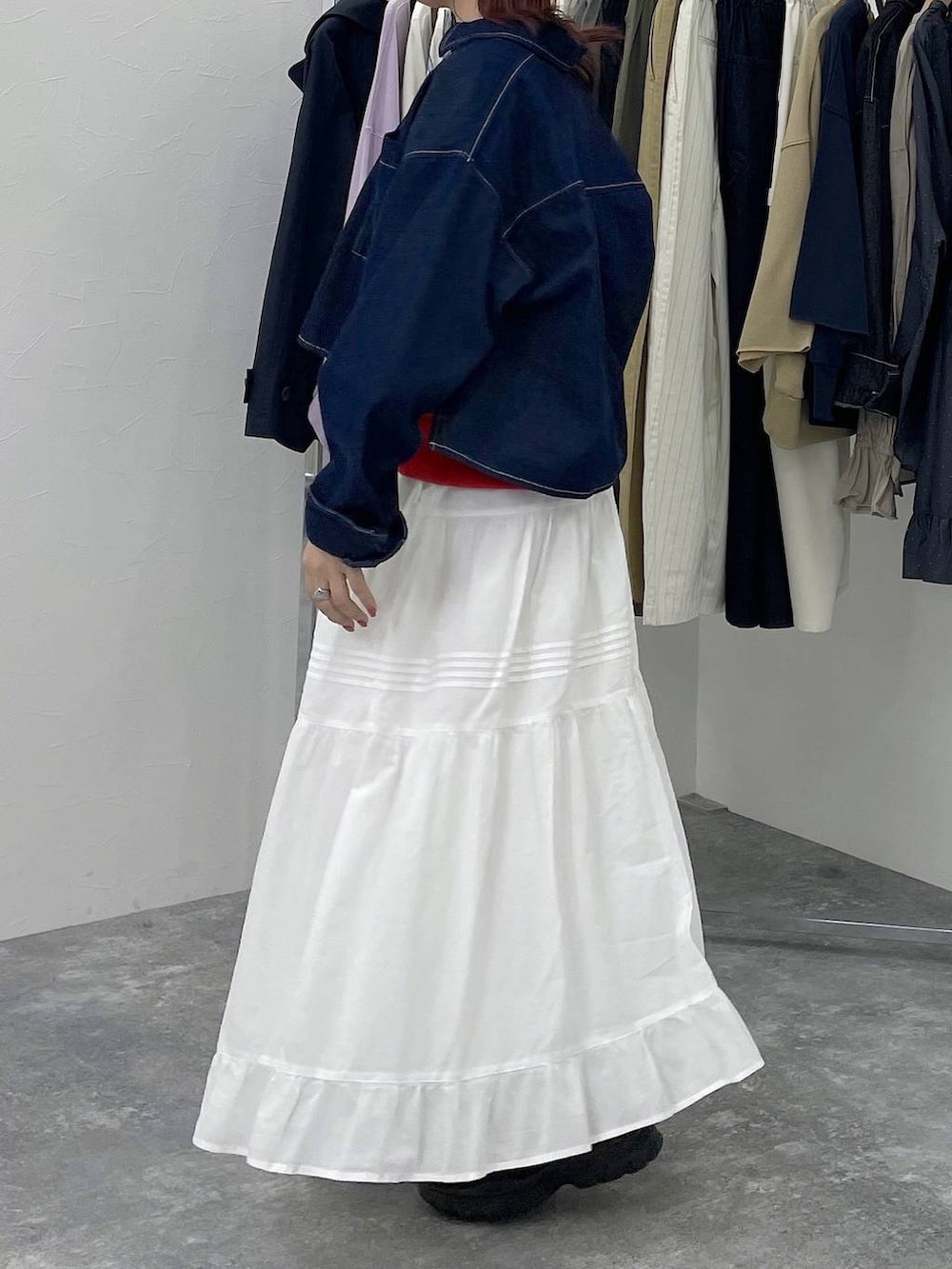 ブラック系のスニーカー、レッド系のスウェット、ホワイト系のスカートを着用したレディースの春コーディネートの5枚目の写真