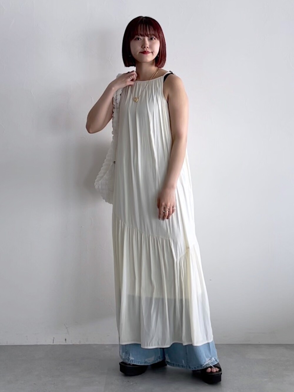 ホワイト系のワンピース、ホワイト系のショルダーバッグ、ブルー系のデニムパンツを着用したレディースの春コーディネートの7枚目の写真