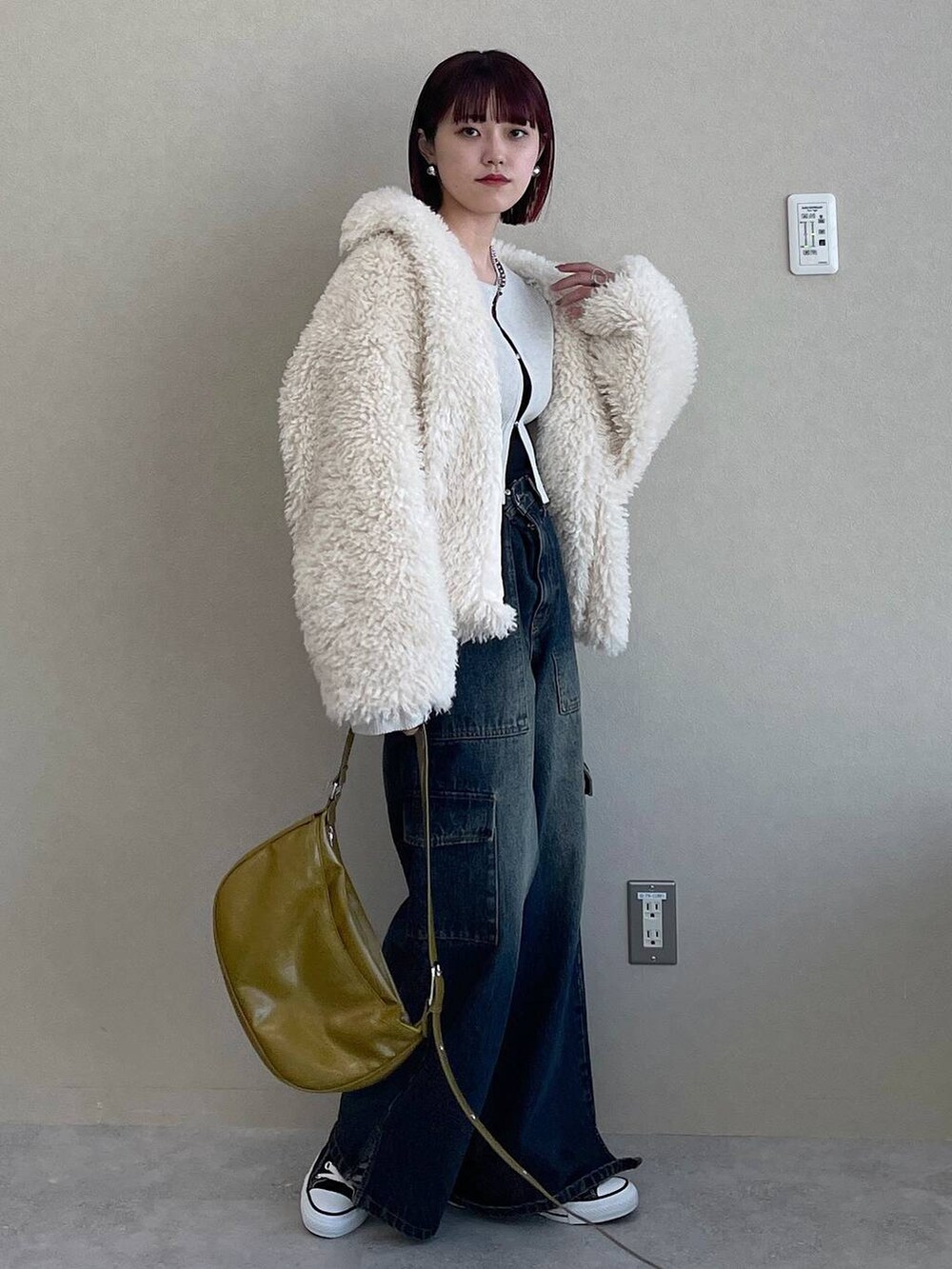 イエロー系のショルダーバッグ、ブルー系のデニムパンツ、ホワイト系のその他アウターを着用したレディースの冬コーディネートの6枚目の写真